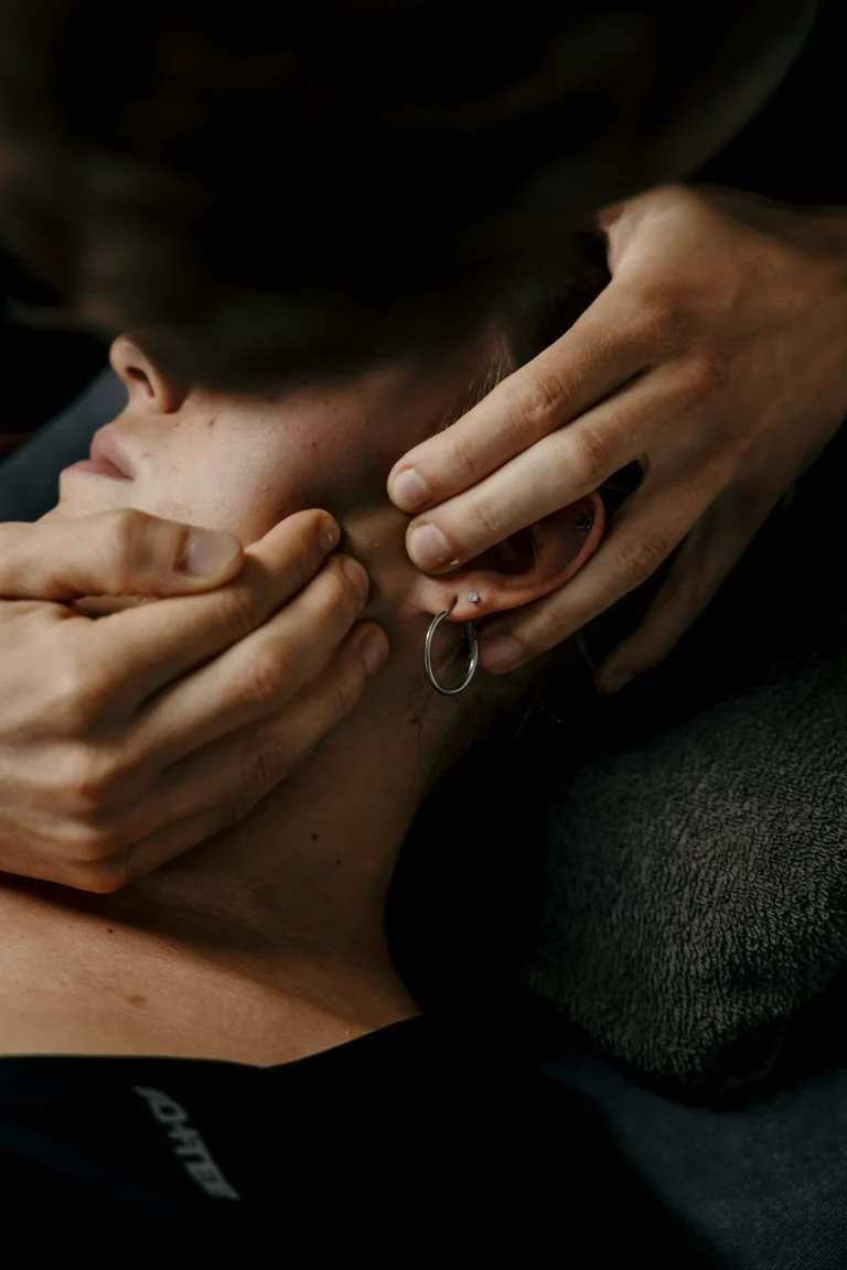 Kinesitherapeut behandelt de kaak en nek van een patiënt met manuele therapie