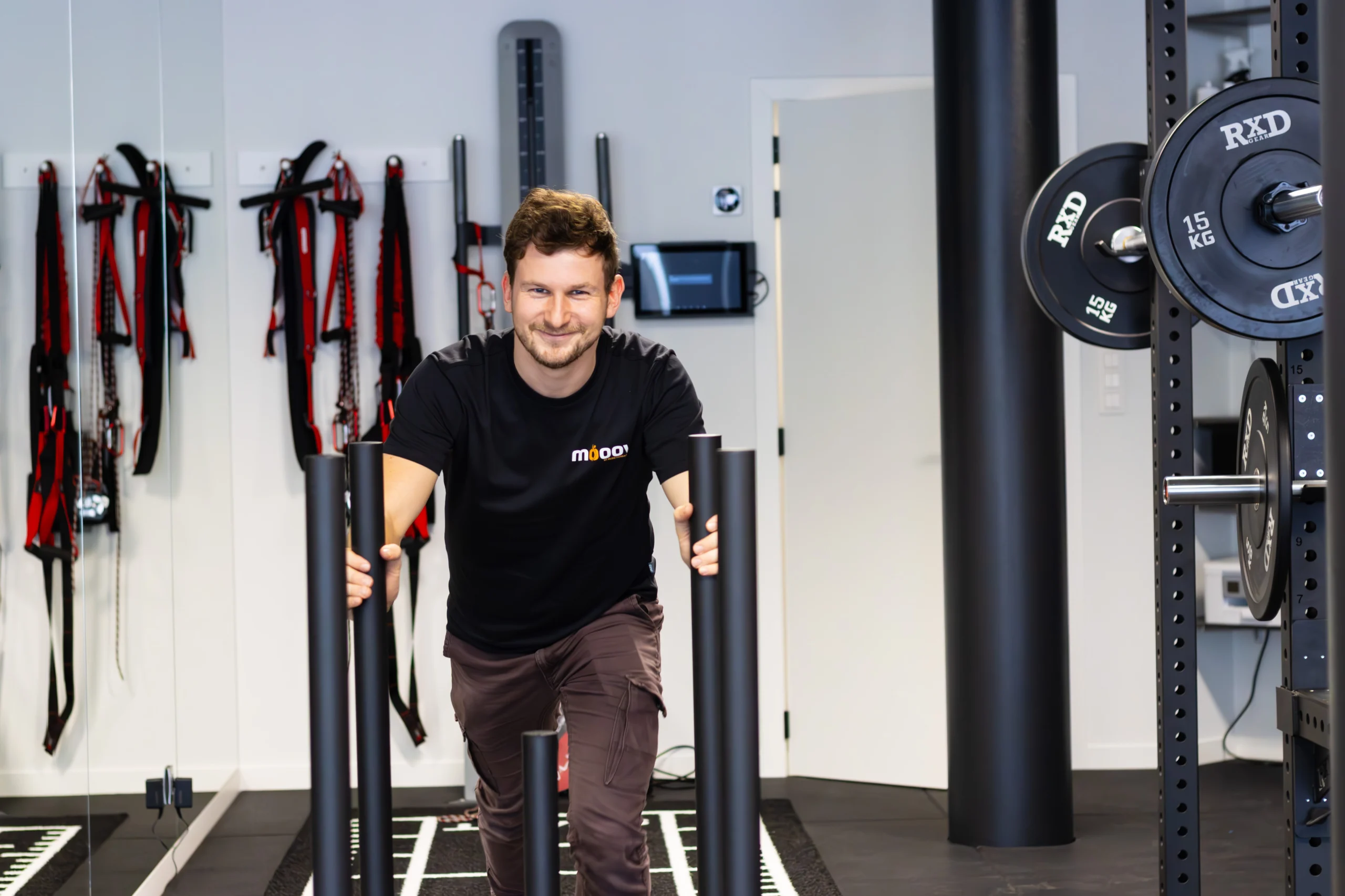 Simon Vyaene duwt lachend een sled over de sprinttrack in de trainingsruimte van MOOOV