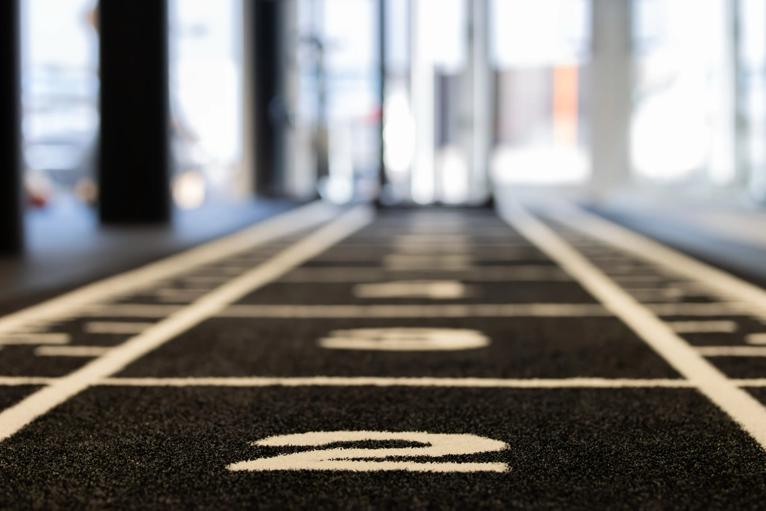 Sprinttrack met witte lijnen en nummers in de trainingsruimte van MOOOV